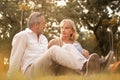 Senior active caucasian couple sitting with relax on the grass floor in the afternoon autumn sunlight with copy space, happily Royalty Free Stock Photo