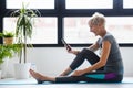 Senior active woman using smart phone at home after practicing yoga Royalty Free Stock Photo