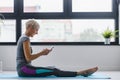 Senior active woman using smart phone at home after practicing yoga Royalty Free Stock Photo