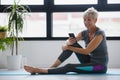 Senior active woman using smart phone at home after practicing yoga Royalty Free Stock Photo