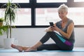 Senior active woman using smart phone at home after practicing yoga Royalty Free Stock Photo