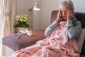 Senior adult caucasian woman with headache and fever symptoms such as seasonal flu or pollen allergy - woman on sofa at home with Royalty Free Stock Photo