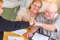 Celebrating Senior Adult Couple Give Fist Bump Over Documents in Their Home with Agent At Signing Royalty Free Stock Photo