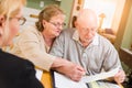 Attentive Senior Adult Couple Going Over Documents in Their Home with Agent At Signing Royalty Free Stock Photo