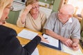 Stressed Senior Adult Couple Going Over Documents in Their Home with Agent At Signing