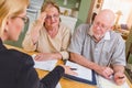 Serious Senior Adult Couple Going Over Documents in Their Home with Agent At Signing Royalty Free Stock Photo