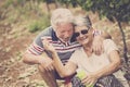 Senior adult couple laugh in happines together forever playing with soap bubbles in the country yard outdoor leisure activity.