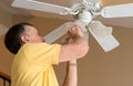 Senior caucasian man replacing bulb in ceiling fan and light Royalty Free Stock Photo