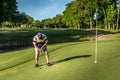 Senior adult man putting the ball on the green, playing golf