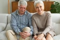 Senior adult mature couple in love looking at camera sitting on couch at home. Portrait of middle age old husband and Royalty Free Stock Photo