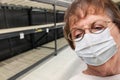 Senior Adult Woman In Medical Face Mask Walking Down Empty Aisle of Grocery Store Royalty Free Stock Photo