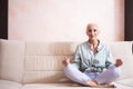 Senior Adults and Yoga Concepts. Portrait of Relaxing Caucasian Senior Woman Posing in Yoga Asana Pose on Couch indoors. Sitting