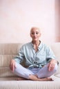 Senior Adults and Yoga Concepts. Portrait of Relaxing Caucasian Senior Woman Posing in Yoga Asana Pose on Couch indoors. Sitting