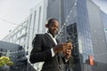 Senior african american businessman in suit standing near office center wearing headphones and listening to music Royalty Free Stock Photo
