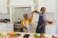 Senior african american couple dancing together in kitchen smiling Royalty Free Stock Photo