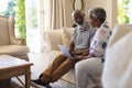 Senior african american couple sitting on sofa using laptop and talking Royalty Free Stock Photo