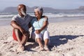 Senior african american couple smiling while looking at each other sitting on the beach Royalty Free Stock Photo
