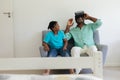 Senior african american grandfather wearing vr headset sitting on couch beside smiling grandson