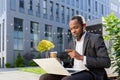 A senior African American male businessman is talking to his team via video call. Sitting near the office center on a Royalty Free Stock Photo