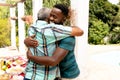 Senior African American man embracing with his son during a family lunch in the garden