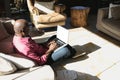 Senior african american man in modern sunny living room working on laptop