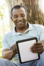 Senior African American Man In Park Using Tablet Computer Royalty Free Stock Photo