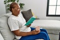 Senior african american woman drinking coffee reading book at home Royalty Free Stock Photo