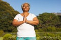 Senior african american woman with eyes closed practicing yoga in stunning countryside