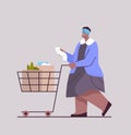 senior african american woman with full of products trolley cart checking shopping list in supermarket Royalty Free Stock Photo