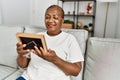 Senior african american woman looking photo sitting on sofa at home