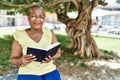 Senior african american woman reading book sitting on the bench at the park Royalty Free Stock Photo