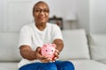 Senior african american woman smiling confident holding piggy bank at home Royalty Free Stock Photo