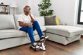 Senior african american woman talking on the smartphone and doing sport using bike pedals machine at home