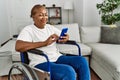 Senior african american woman using smartphone sitting on wheelchair at home Royalty Free Stock Photo
