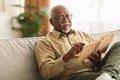 Senior African Man Reading Book Sitting On Couch At Home Royalty Free Stock Photo