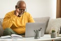 Senior African Man Squinting Eyes Using Laptop Wearing Eyeglasses Indoor