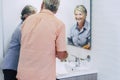 Senior age caucasian couple in the bathroom at home washing hands. Happy mature people getting ready in the morning. Hotel and Royalty Free Stock Photo