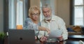 Senior aged couple checking accountancy and bills. Older retired couple holding computer and financial paper documents Royalty Free Stock Photo