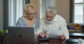 Senior aged couple checking accountancy and bills. Older retired couple holding computer and financial paper documents Royalty Free Stock Photo