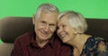 Senior aged man and woman sitting together on a sofa and smiles. Chroma key