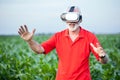 Senior agronomist or farmer standing in corn field and using VR goggles