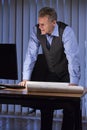Senior architect, businessman or engineer standing at a desk with blueprint