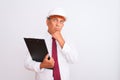 Senior architect man wearing security helmet holding clipboard over isolated white background serious face thinking about Royalty Free Stock Photo