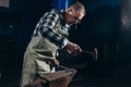 Senior an artisan blacksmith knocks with a hammer on iron to shape Royalty Free Stock Photo