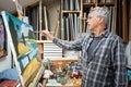 Senior artist painting on canvas in his studio