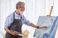 mature artist painting on easel, canvas