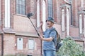 Senior Asian blogger shooting video for his blog on social network near wall of Cathedral, Kaliningrad, Russia Royalty Free Stock Photo