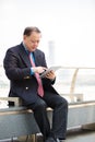 Senior Asian businessman in suit using tablet PC Royalty Free Stock Photo