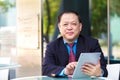 Senior Asian businessman in suit using tablet PC Royalty Free Stock Photo