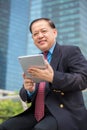 Senior Asian businessman in suit using tablet PC Royalty Free Stock Photo